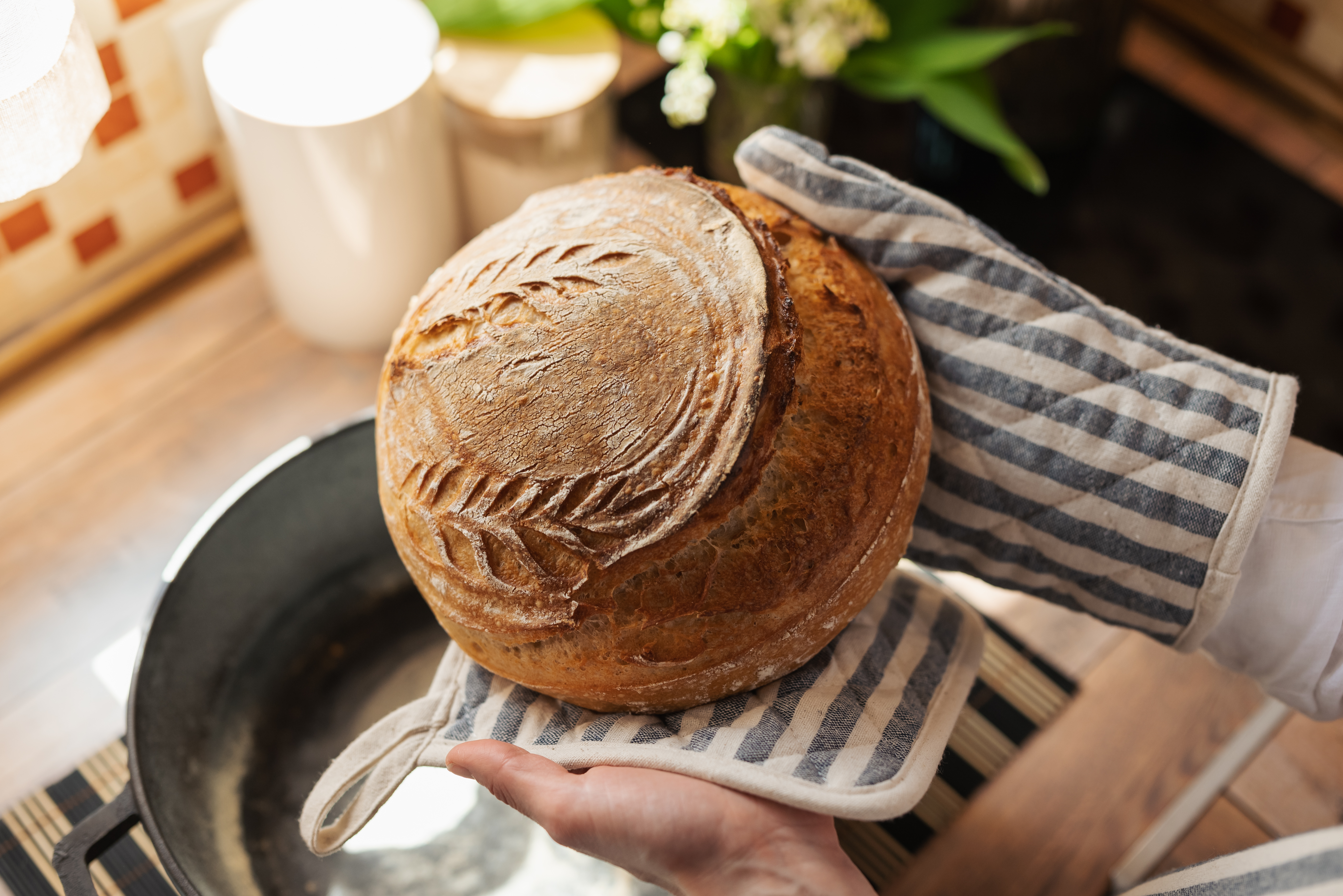 Homemade wheat bread in female hands on kitchen background. Beautiful, fresh, aromatic, hot bread, close up